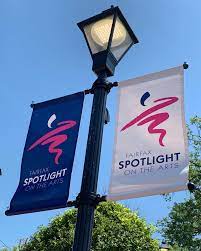 A street lamp has two flags, one navy and one white. Both flags have a logo that says "Spotlight on the Arts"