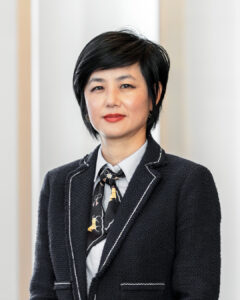 Woman wearing black suit and white shirt with short black hair looking at camera