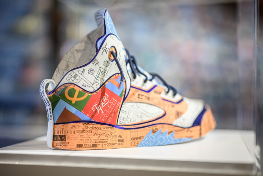 A close up of a shoe modeled after an Air Jordan 5 is made of recycled paper including building plans for Tysons Corner Center, a shopping destination